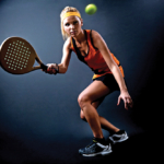 Beautiful woman playing padel indoor. Isolated on black.