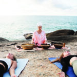 senior-meditation-guide-with-singing-bowls-beach